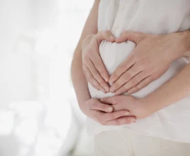 Dłonie obejmujące brzuch kobiety w ciąży